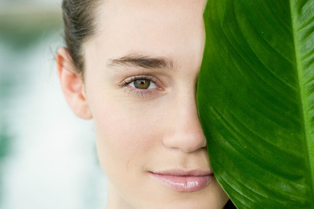 young lady covering eye with leaf