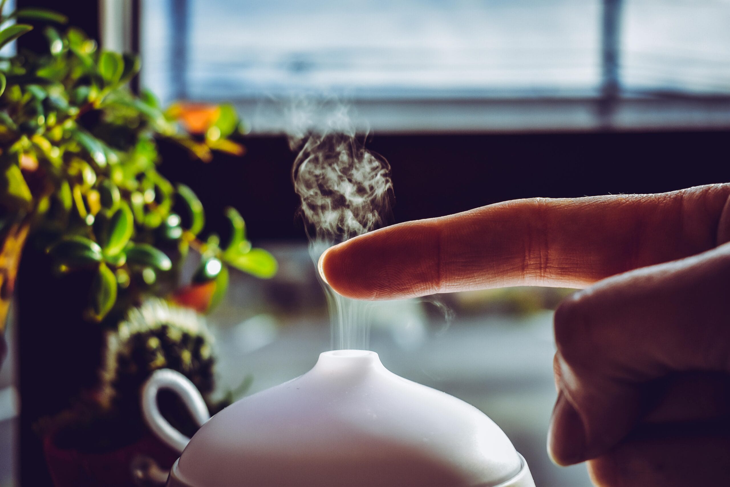 pexels photo 1582457 1582457 A hand touches mist rising from a diffuser, creating a relaxing ambiance indoors.